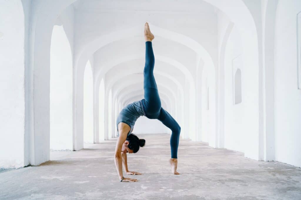 woman doing backbend pose under white arches